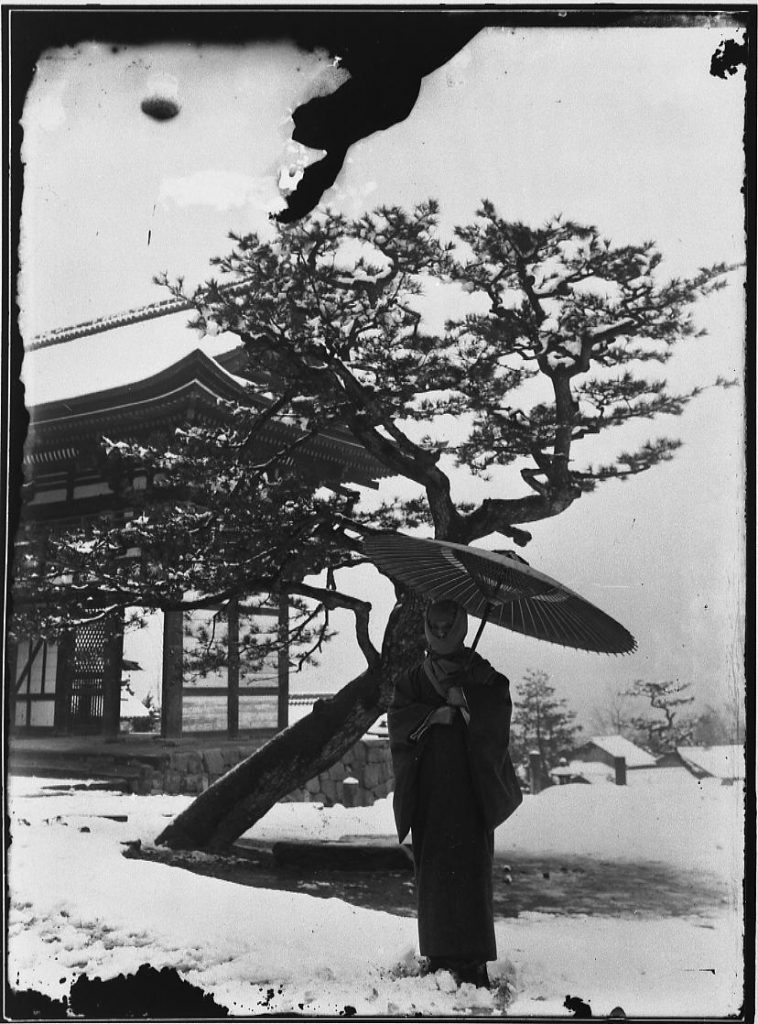 雪の三門に立つ女性