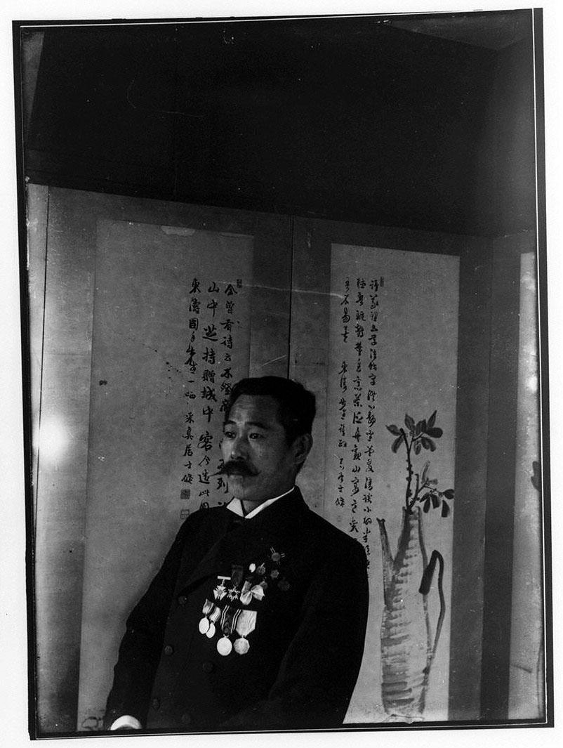 屏風前の勲章をつけた男性